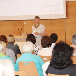 Eine Referentin spricht vor einem aufmerksamen Publikum bei einer Weiterbildungsveranstaltung in der Akademie Heiligenfeld. Der gut besuchte Seminarraum unterstreicht das Engagement der Teilnehmenden für ihre persönliche und berufliche Fortbildung.